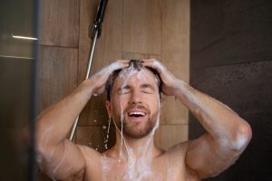 A man is using the shower mixer
