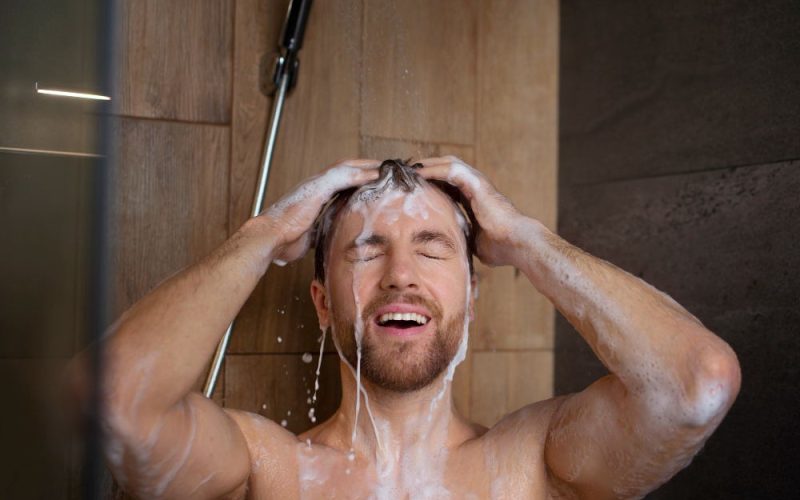 A man is using the shower mixer