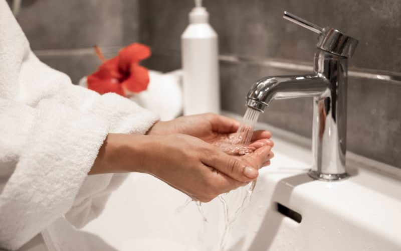 a woman using the bathroom faucet
